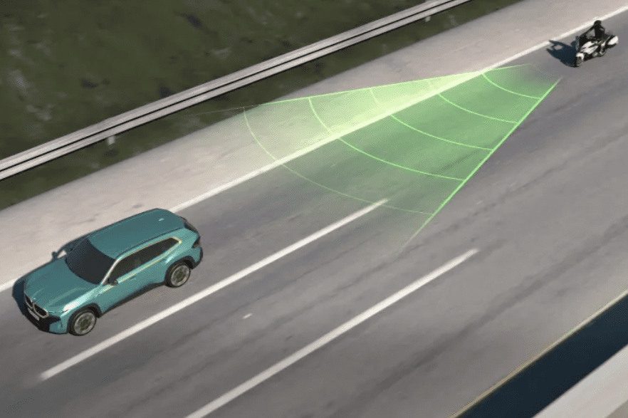 Moto viaja detrás de auto y proyecta un triángulo ilustrativo del radio que abarca el aviso de colisión BMW