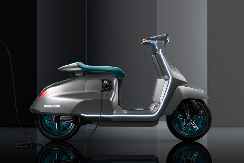 Scooter Elettra gris con asiento y ruedas turquesa recargándose
