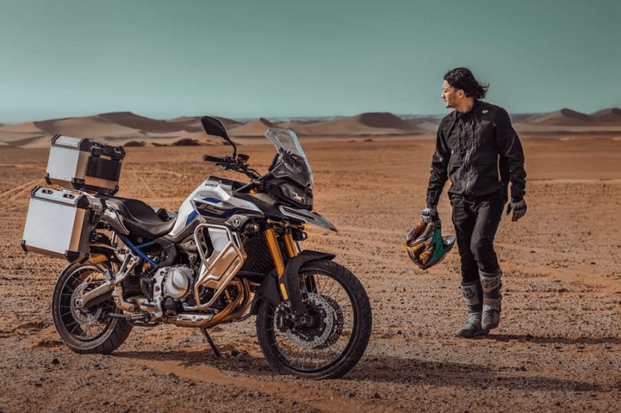 Equipaje para viajar en moto: opciones, consejos y productos Un viajero en Voge Valico DS900X camina por el desierto en torno a la moto