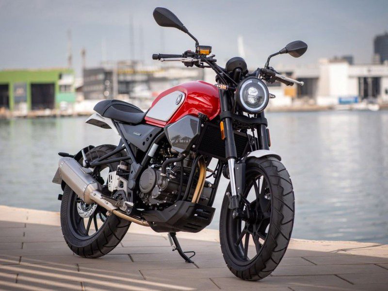 <img data-src="https://motodinamia.com/wp/wp-content/uploads/2023/12/Hanway_SC_125-mdm-2.jpg" alt="En la Hanway SC 125 Scrambler se distinguen un faro circular con luces LEDs superpuestas, con una guía luminosa en derredor para las luces de posición, y un diminuto piloto trasero incrustado debajo del asiento">