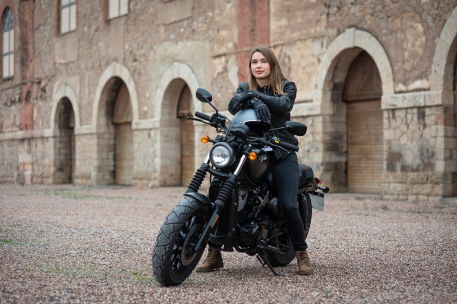Una joven apoyada en su casco sobre el depósito de la Bobber