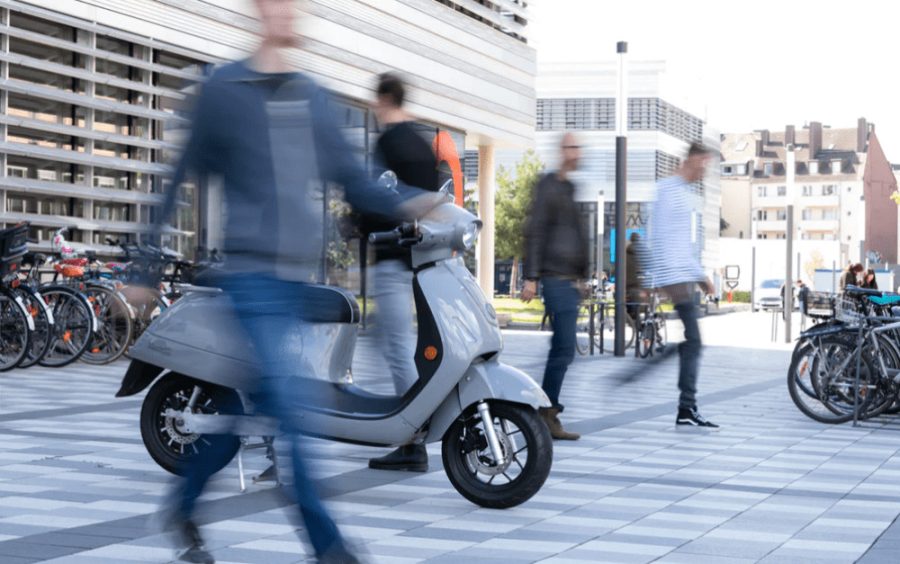 Foto de un scooter Switch Motion en foco mientras la gente de alrededor esta movida