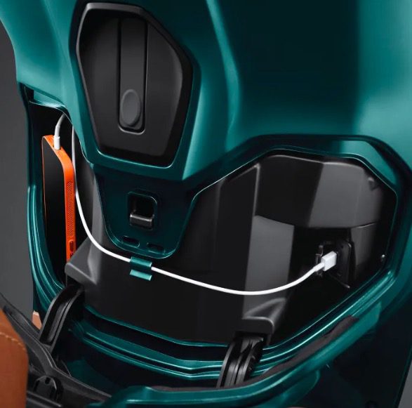 Un celular se recarga en el puerto USB de un scooter verde