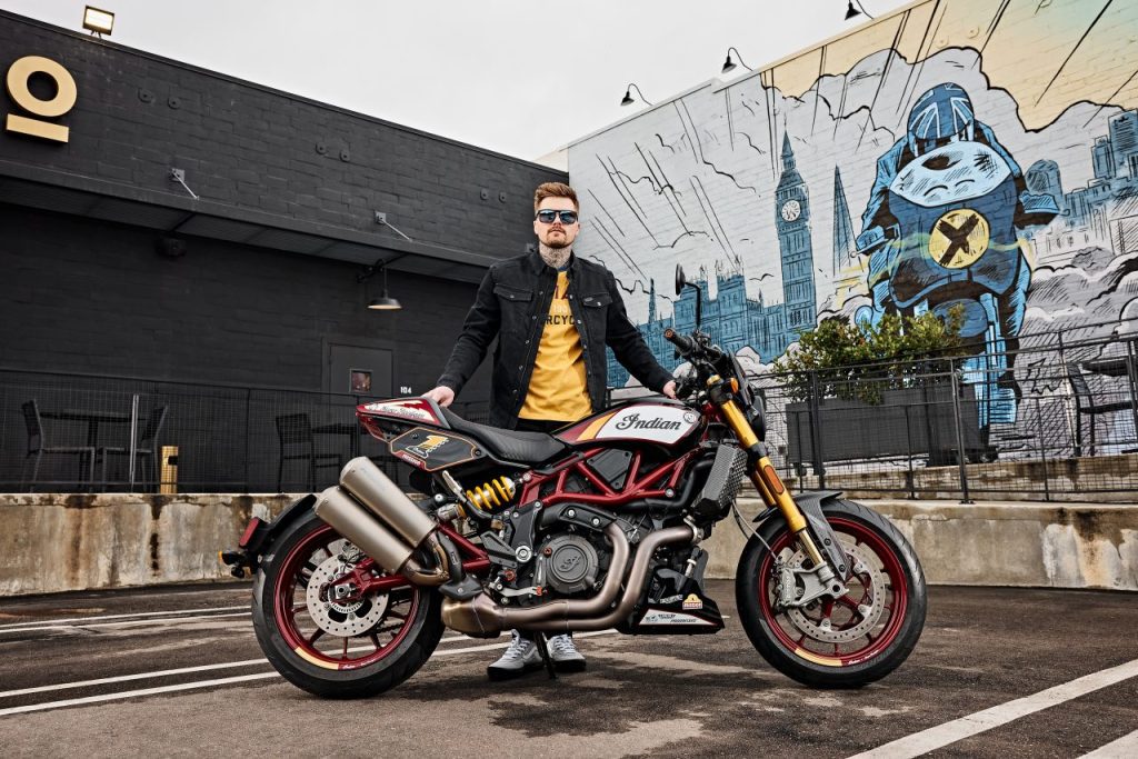El propio Roland Sands posa junto a una Indian FTR R Carbon, con graffitis de fondo