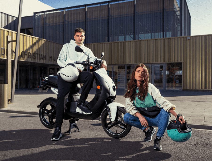 Chico y chica junto a un Peugeot E-Ludix blanco
