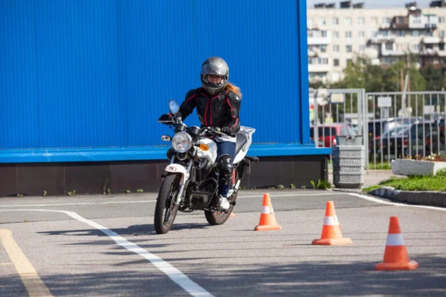 Una motociclista ensaya el tradicional slalom entre conitos en un curso de seguridad