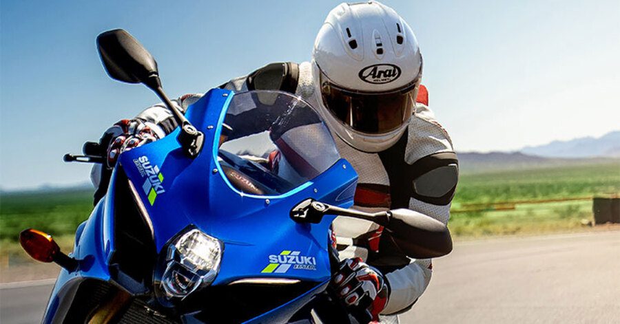 Un piloto con el casco Arai RX-7V EVO RACING FIM #2 se desplaza en una Superdeportiva azul