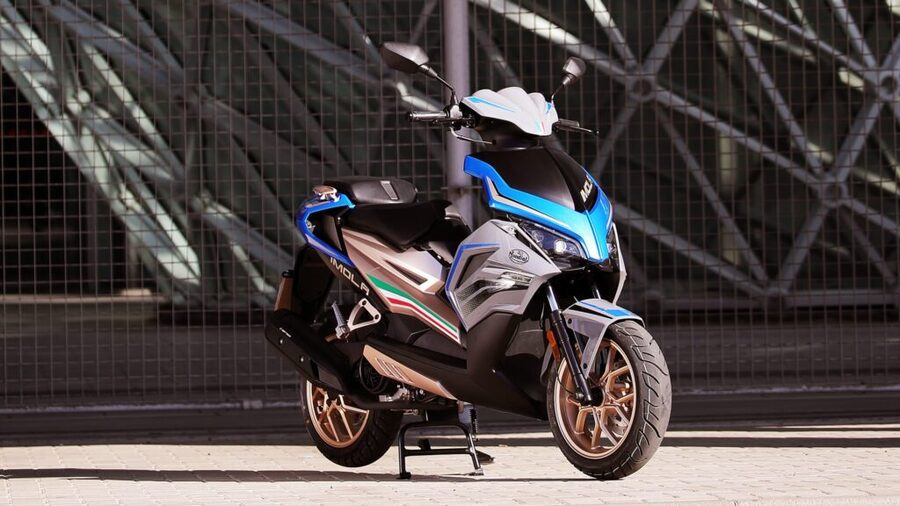 FB Mondial Imola 125: esencia deportiva Un Scooter FB Mondial Imola 125 azul con llantas doradas sobre su caballete central