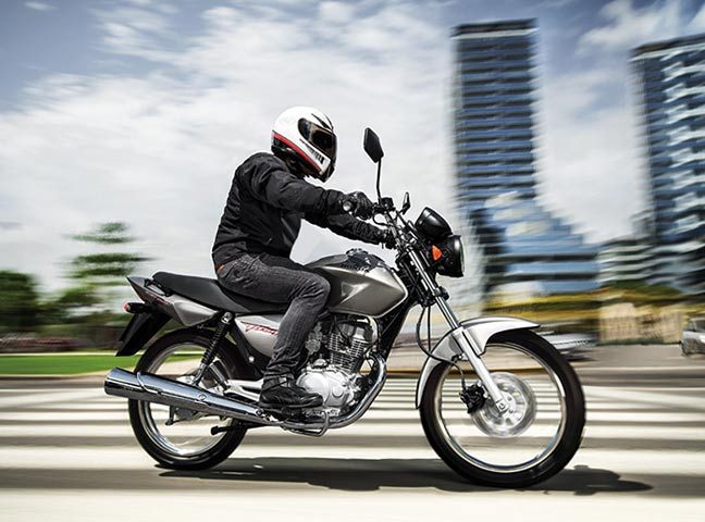 Una moto street de color gris de baja cilindrada circula por una ciudad