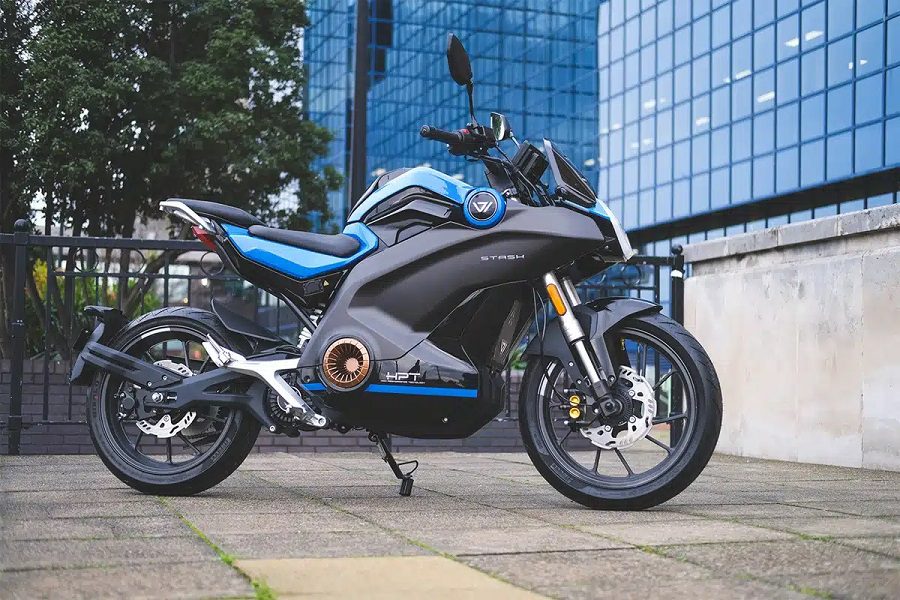 Vmoto Stash azul con un edificio vidriado de fondo