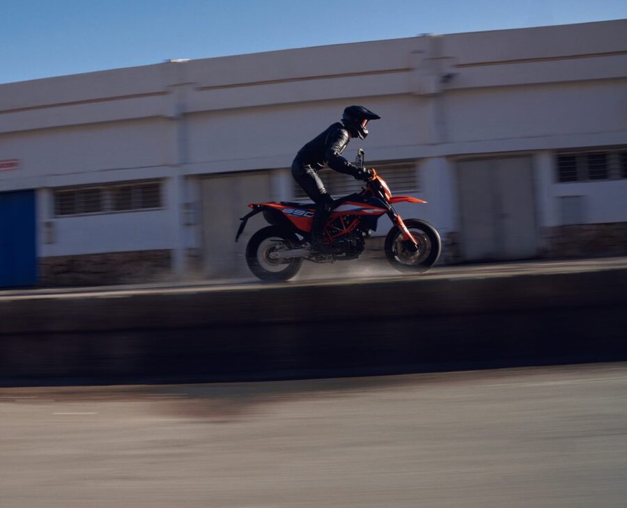Una supermotard con el piloto parado sobre los estribos se traslada a gran velocidad sobre una explanada de concreto