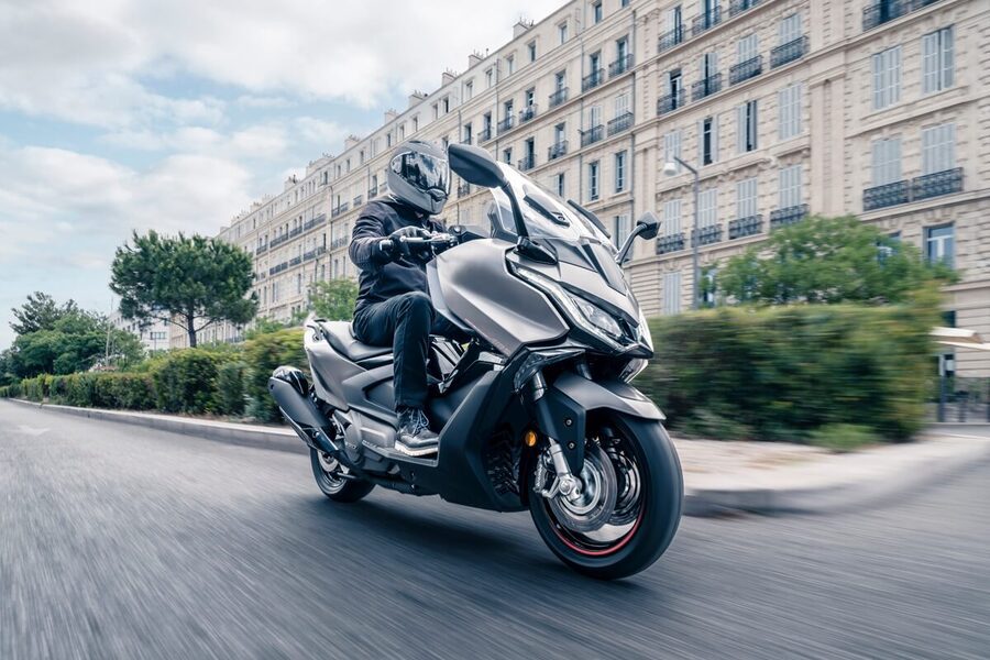 Un KYMCO AK 550 Premium gris metalizado se desplaza por un ciudad