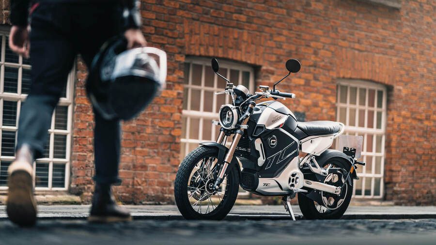 Un hombre casco en mano se acerca a una Super Soco TC Max