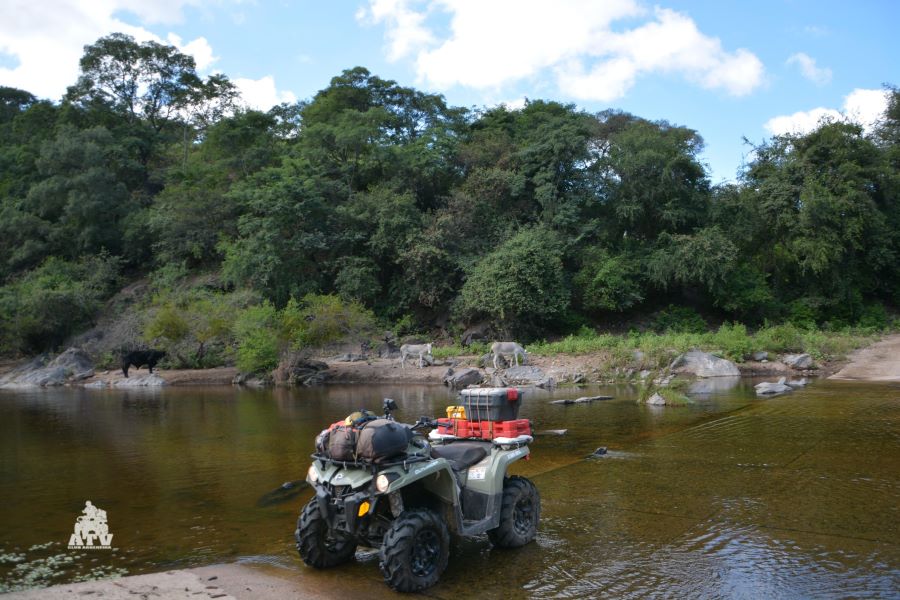 Un ATV solo y parado sobre un vado en un río de montaña.
