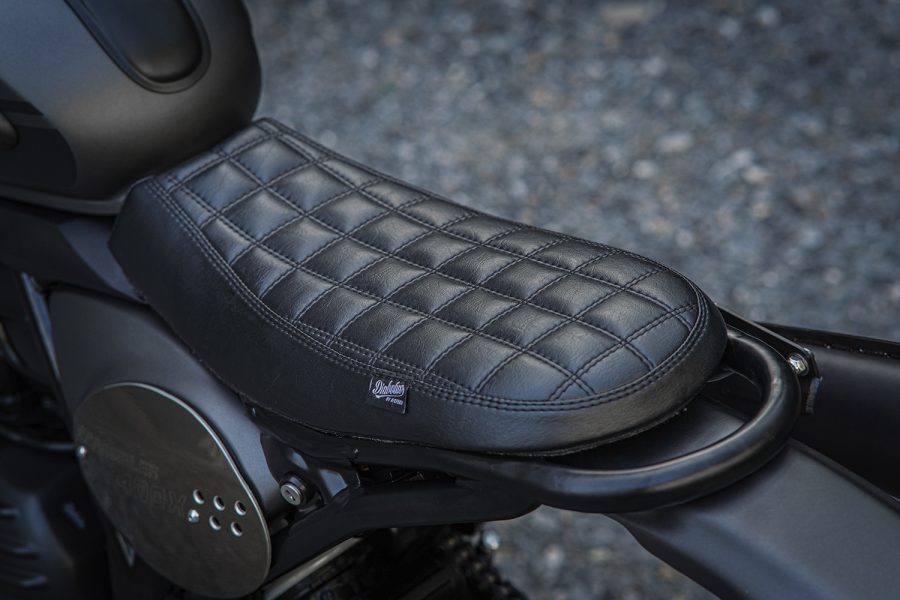 Asiento de cuero negro y pespunteado en cuadrados pequeños, resalta el estilo de la Diabolus Scrambler de K-Speed