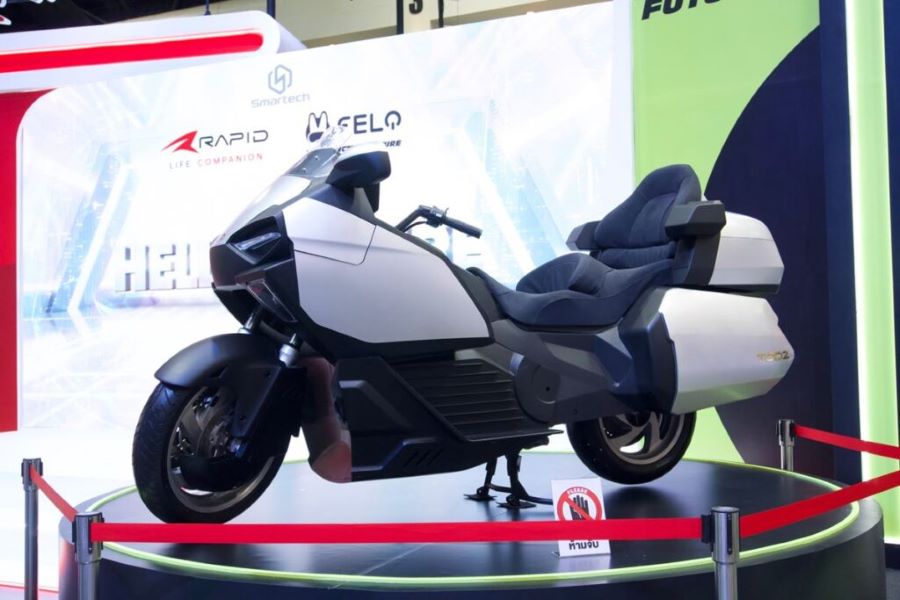 La moto Grand Turismo eléctrica Felo Tooz, blanca y con maletas, se exhibe en un stand en Bangkok.