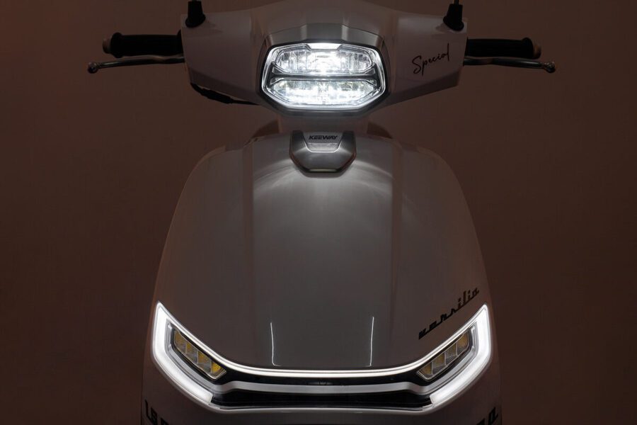 Frontal de un Scooter Versilia 125 gris con el faro encendido y las luces de giro apagadas.