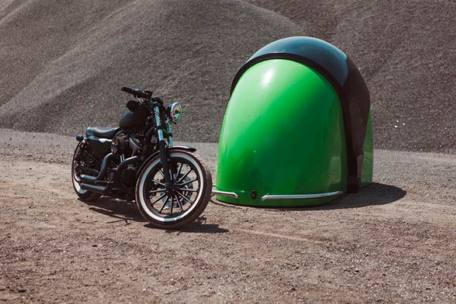 Una moto Chopper negra al lado de una Qbean Moto Garage mitas verde y mitad negro.