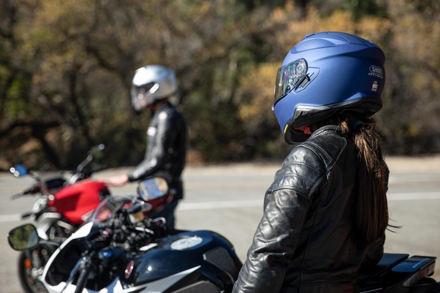 Un hombre y una mujer con sus cascos SHOEI con el intercomunicador SENA SRL-Mesh