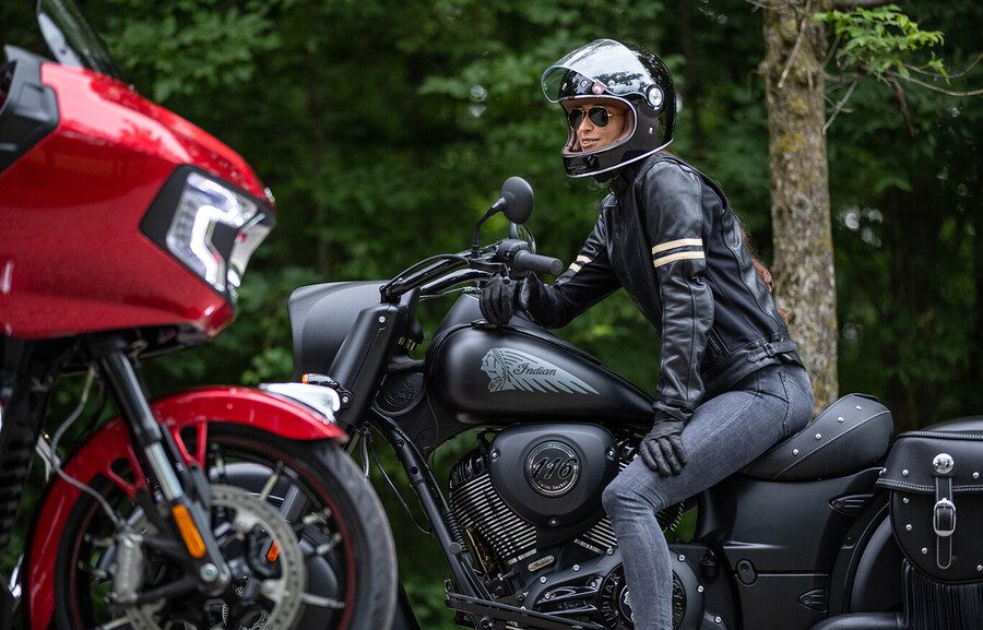 ropa-calefaccionable-indian Una mujer con una chaqueta y un pantalón "calefaccionable" sobre una moto Indian negra