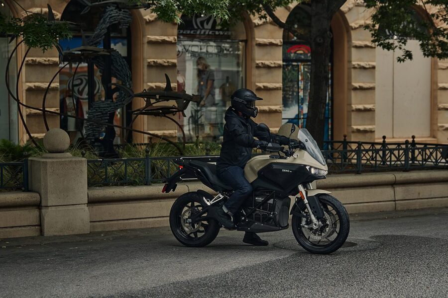 Un conductor sobre una Zero DS 2024 beige al lado de una escultura de hierro negro.