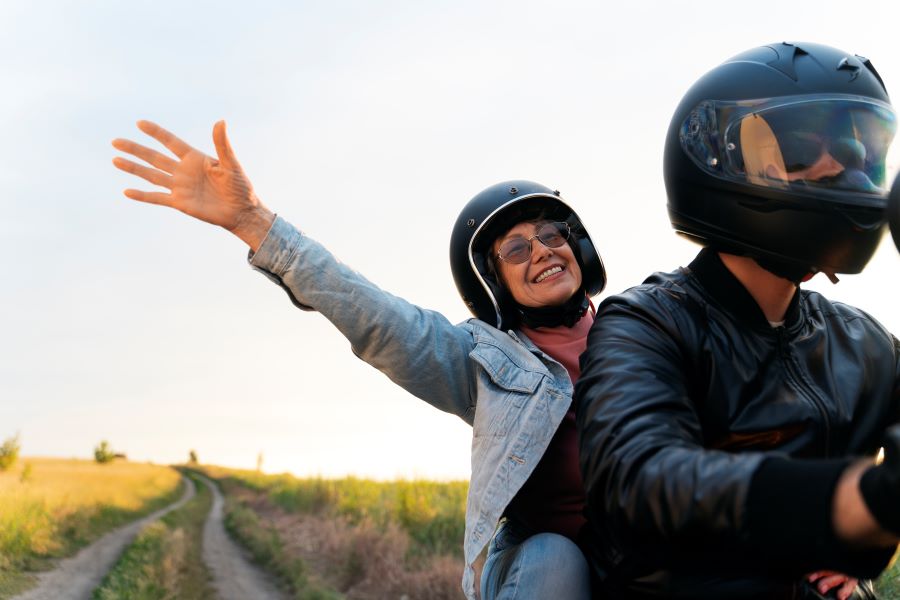 Cómo bajarse de una moto de copiloto de forma correcta y segura Una mujer de pasajera en una moto extiende su brazo feliz