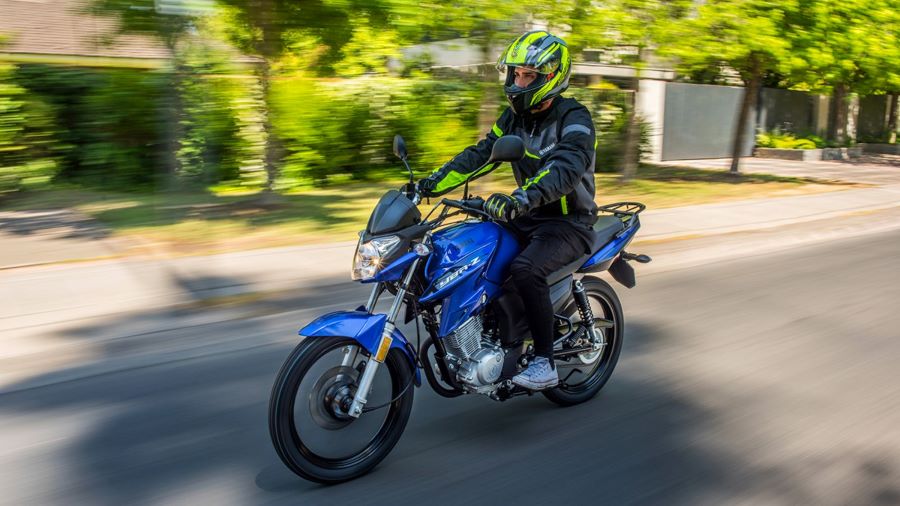Cómo andar en moto: Guía completa para ganar confianza Un motociclista maneja una Yamaha YBR 125 azul metálico con la ropa adecuada y casco