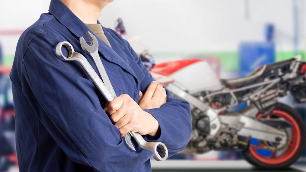 Un mecánico de motos sostiene dos llaves en sus manos