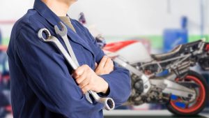 Un mecánico de motos sostiene dos llaves en sus manos