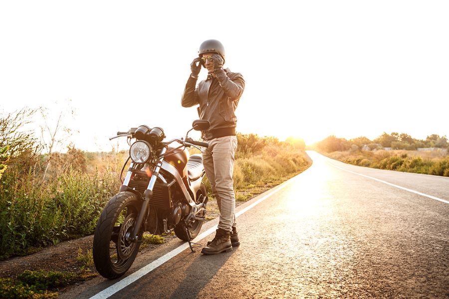 Frases para moteros 2 Motociclista parado al lado de su moto en medio de una ruta asfaltada pero desierta