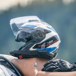 Schuberth J2: Ni jet ni integral, con mentonera desmontable Casco Schuberth J2 y guantes negros sobre el asiento de una moto.