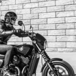 Foto monocromática de una mujer se desplaza sobre una Harley-Davidson Street 500 por una calle.