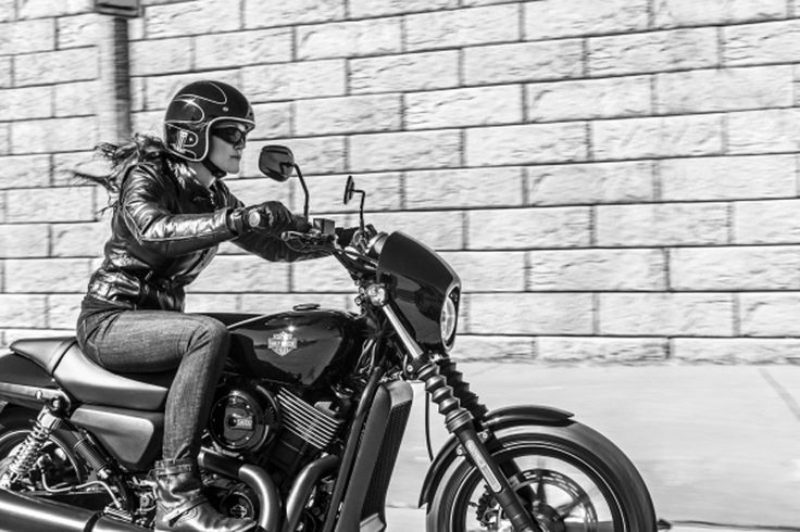 Foto monocromática de una mujer se desplaza sobre una Harley-Davidson Street 500 por una calle.