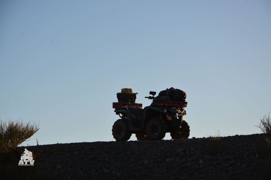 La figura oscura de un ATV se recorta entre la tierra y el cielo de la precordillera andina.