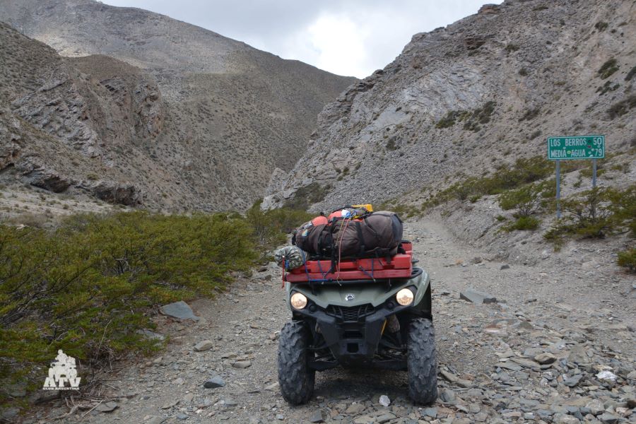 Un ATV cargado de bártulos y con las luces encendidas, sobre una camino de montaña de San Juan.