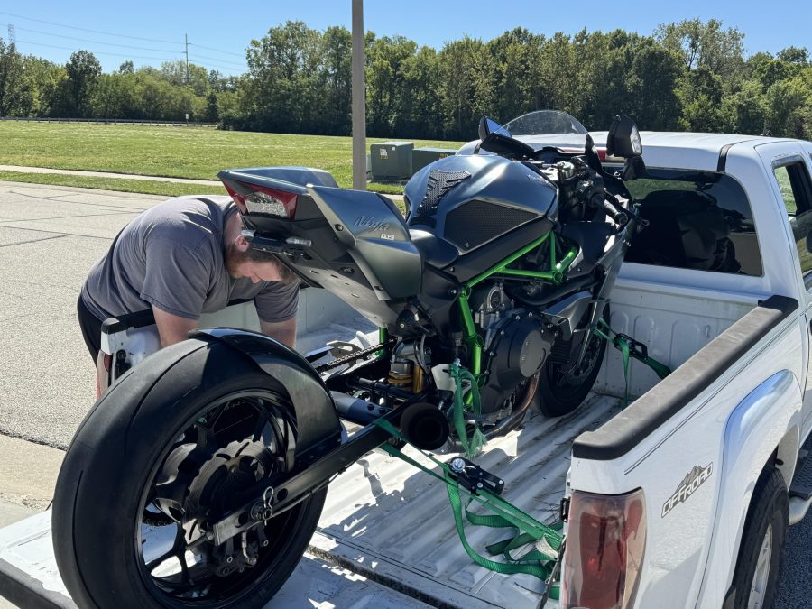 Una persona está sujetando una moto superdeportiva con tensores a la caja de una camioneta,