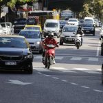 Conducción segura en moto: clave para salvar vidas Una motocicleta de color rojo circula en medio de los carriles y entre autos en una avenida de Buenos Aires.