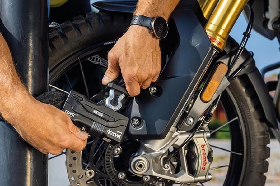 Una persona fija su moto con un candado de máxima seguridad.