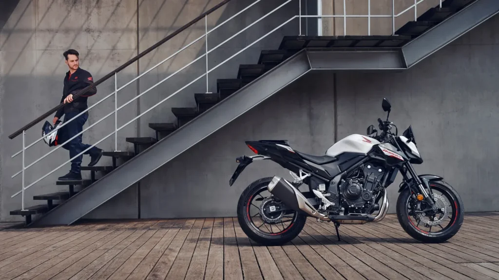 Un hombre baja por una escalera en busca de su Honda CB500 Hornet blanca.