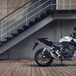 La Hornet de 500 cc vuelve con prestaciones mejoradas Un hombre baja por una escalera en busca de su Honda CB500 Hornet blanca.