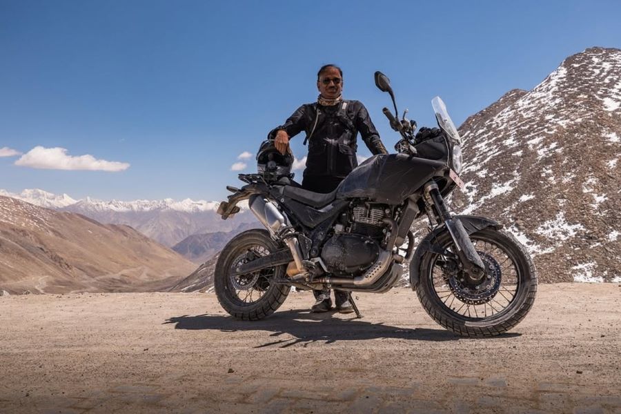 Un directivo de Royal Enfield posa detrás e un prototipo de Hinalayan 750 en la montaña