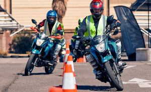 Dos motos avanzan en zig zag entre conitos naranjas durante una clase de manejo