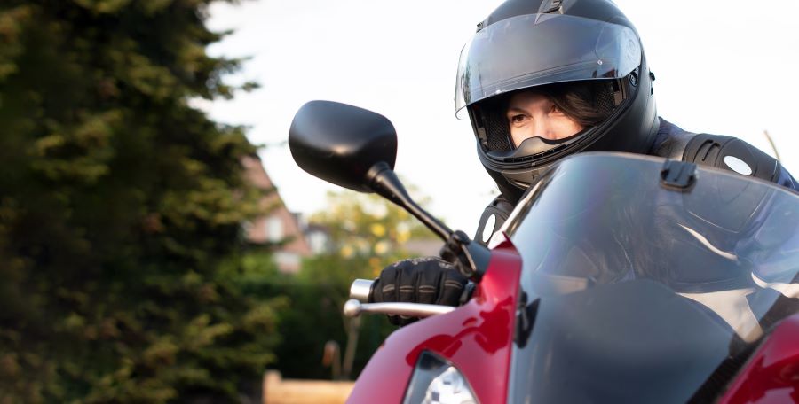 Una mujer con el casco puesto mira el espejo retrovisor antes de subirse a la moto