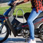 Mejores motos para uso diario: Ideales para la ciudad Un joven, al que no se le ve el rostro, está sentado sobre una Zanella ZB 100 gris con detalles rojos