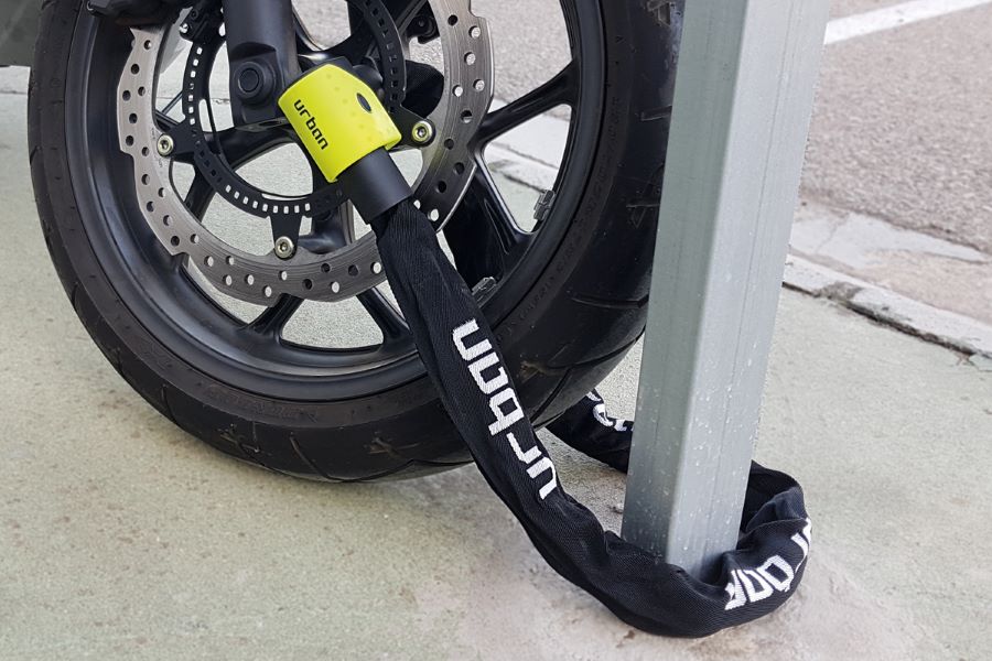 Una cadena con candado lía la moto a una barra en un estacionamiento. 
