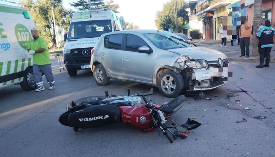 Una moto semi destruida permanece tirada en el asfalto a un costado de un auto con el que protagonizó un choque. 