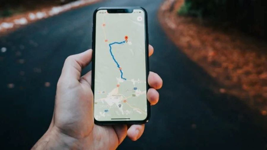 En la pantalla de un celular sostenida por la mano izquierda se observa un recorrido de Google Maps