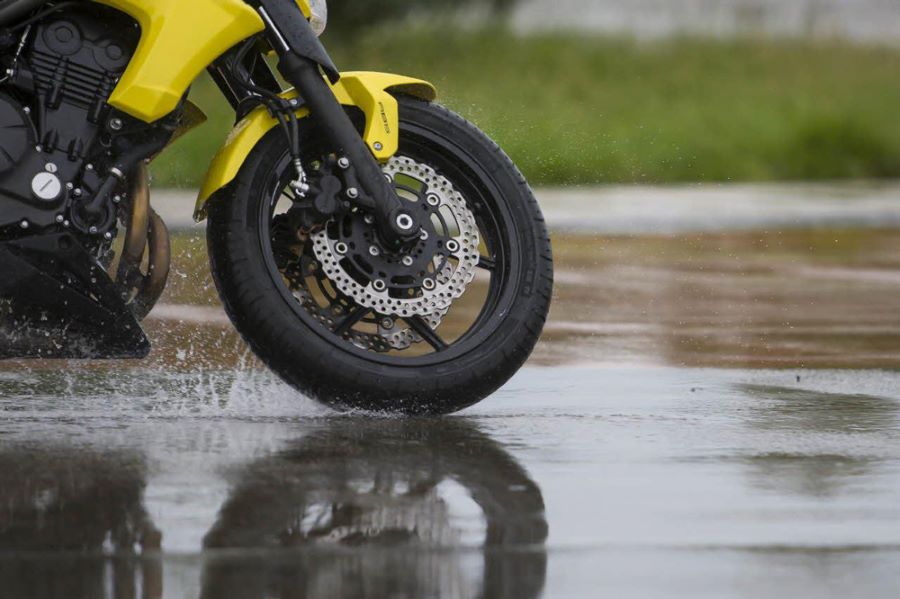 Rueda delantera de una moto deportiva amarilla durante una frenada en mojado