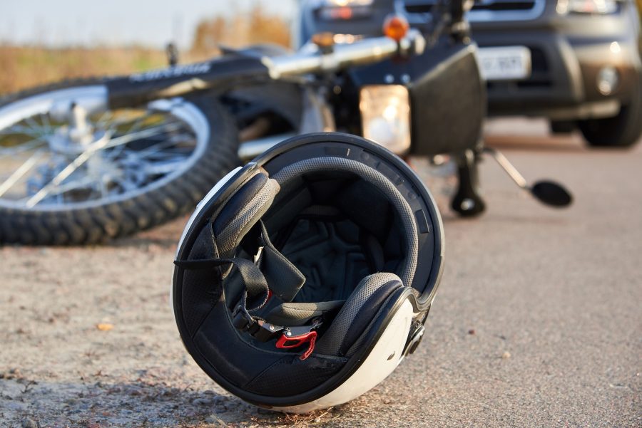 Casco moto desprendido En primer plano un casco tirado sobre la calzada y más atrás una imagen desenfocada de una moto accidentada