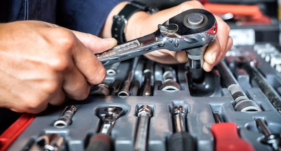 Un mecánico de motos trabaja con un juego de llaves combinas y tubos